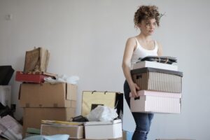 Woman carrying a few cardboard boxes, ready to move and downsize her home