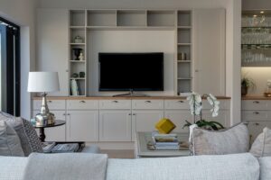 A room with white furniture and a TV in the central position