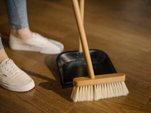Person cleaning the home floor with a broom